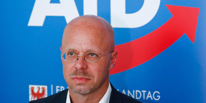 Porträtfoto von Andreas Kalbitz vor einem AfD-Plakat