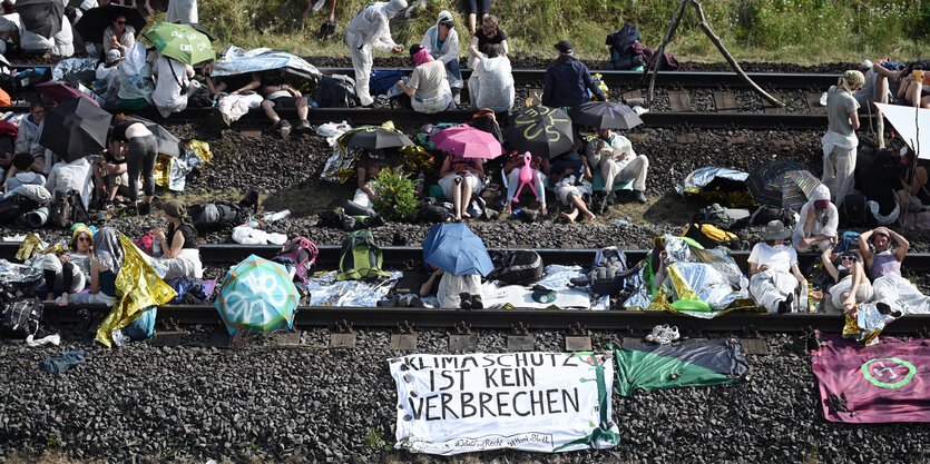 Klimaschützerinnen und Klimaschützer blockieren Gleise in weißen Anzügen