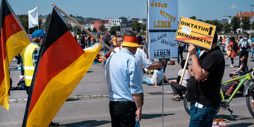 Drei Männer von denen einer eine skurrile Maskierung trägt