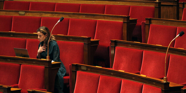 Eine französische Abgeordnete sitzt allein auf einem der Ränge in der französischen Nationalversammlung