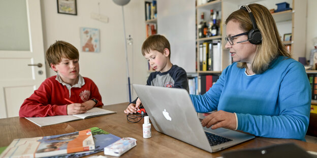 Frau mit Laptop und Kindern am Küchentisch Frau mit Laptop und Kindern am Küchentisch