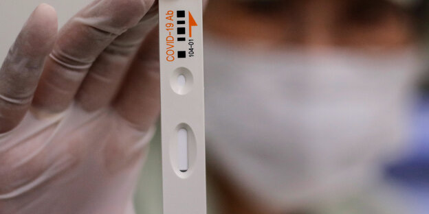Ein Mitarbeiter von Boditech Med hält ein Teströhrchen für einen Covid-19-Antikörpertest in der Hand.