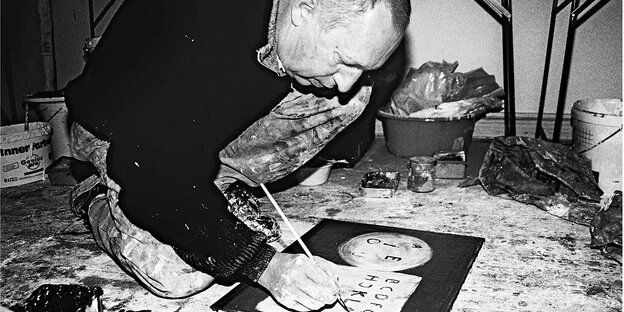 Norbert Schwontkowski malt am Boden kauernd
