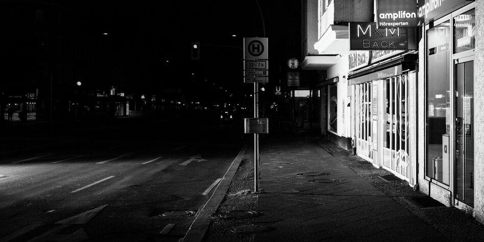 Eine Straße mit Bushaltestelle im Dunkeln.