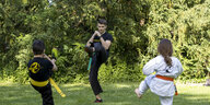 Kampfsportlehrer mit zwei Kindern beim Training im Park