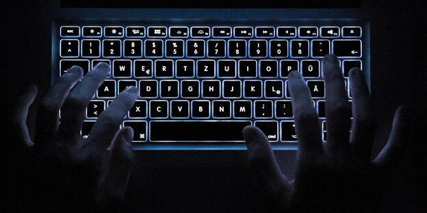 Hände tippen auf der beleuchteten Laptoptastatur