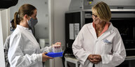 Zwei Frauen in weißen Kitteln und Gesichtsmaske stehen in einem Labor