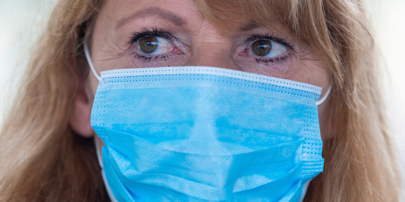 Frau mit blondem Haar und blauer Schutzmaske