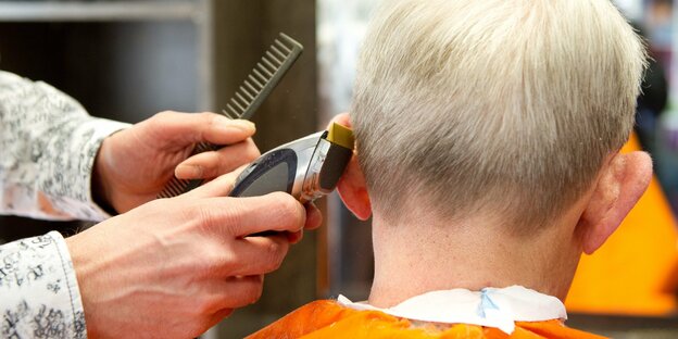 Friseurin schneidet einem Kunden die Haare