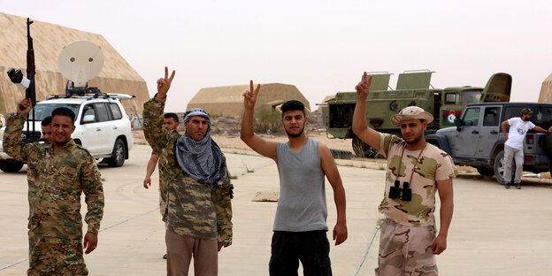 Kämpfer posieren in Siegesposen auf der eroberten Luftwaffenbasis Watia