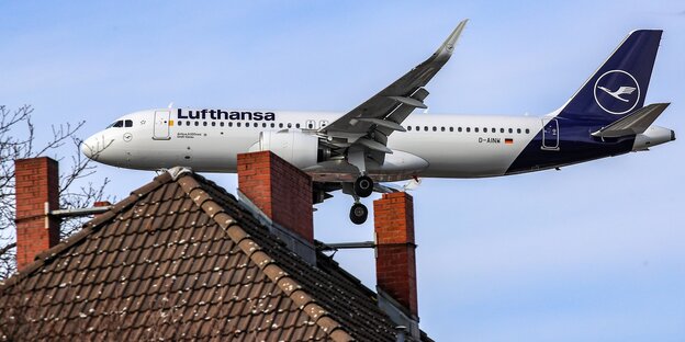 Maschine der Lufthansa im Landeanflug direkt über einem Dach