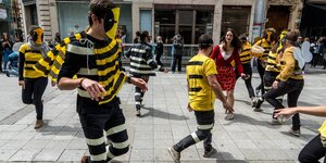 Menschen haben sich in schwarz-gelbe Kostüme verkleidet und demonstrieren auf der Straße