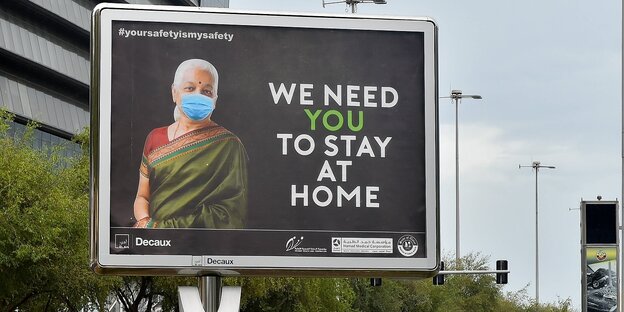 Ein Plakat zeigt eine Frau mit Mundschutz und den Slogan "We need You to stay at home"