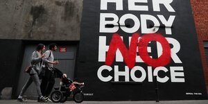 Eltern mit Kinderwagen gehen in Dublin an einem Poster der Künstlergruppe Subset vorbei, das mit der Aufschrift "Ihr Körper Keine Wahl" zu einer Reform der Abtreibungsgesetze aufruft.