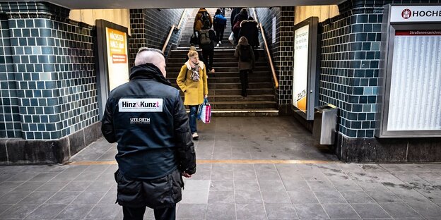 Ein Verkäufer der Straßenzeitung Hinz&Kunzt steht an einer U-Bahn Treppe