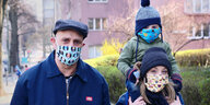 Vater, Mutter und Kind, alle tragen Mundschutzmasken