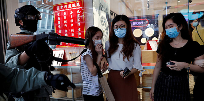 ein sehr junger Demonstrant ist in Hong Kong von Pilizisten umringt