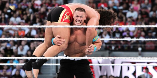 Wrestler John Cena trögt einen anderen Wrestler.