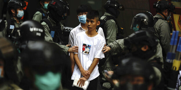 Ein sehr junger Demonstrant ist von Polizisten umringt