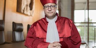 Mann mit roter Robe und Mütze in einem Saal