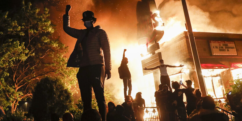 Demonstarnten vor brennendem Haus.