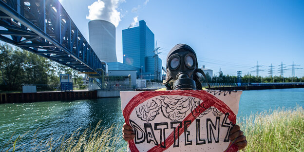 Ein Demonstrant mit Gasmaske und einem Verbotsschild, auf dem steht "Datteln 4" vor einem Kohlekraftwerk