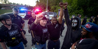 protestierende Menschen mit gereckter Faust, die von Polizisten umgeben sind