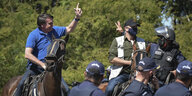 Ein Mann auf einem Pferd grüßt Menschen, einige davon tragen Polizeiuniformen.