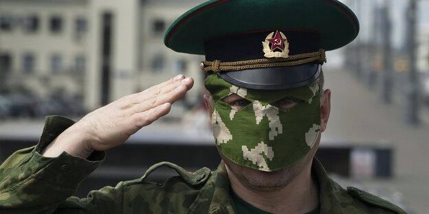 ein salutierender Soldat mit Camouflage- Mundschutz