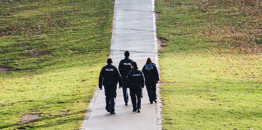 mehrere polizisten laufen durch einen park