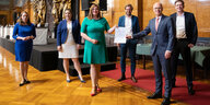 Eine gruppe von Politiker*innen in Hamburg. Sie halten einen Zettel in die Höhe: den Koalitionsvertrag