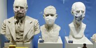 Drei Statuen tragen Atemschutzmasken