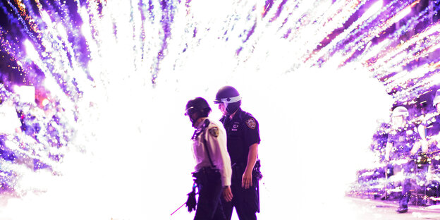 Zei Uniformierte vor einem explodierenden Feuerwerkskörper.