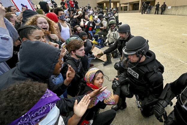 Polizisten und Demonstranden knien und ein Polizist reicht einer Frau die Hand