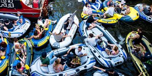 Menschen feiern dicht nebeneinander auf Schlauchbooten