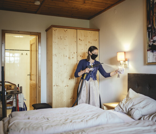 Ein eFrau desinfiziert ein Hotelzimmer.