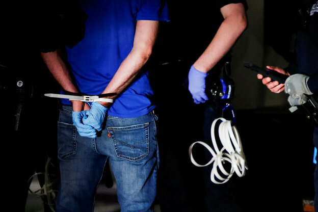 Hände eines Festgenommenen und eines Polizisten mit Schutzhandschuhen. Hände eines Festgenommenen und eines Polizisten mit Schutzhandschuhen.