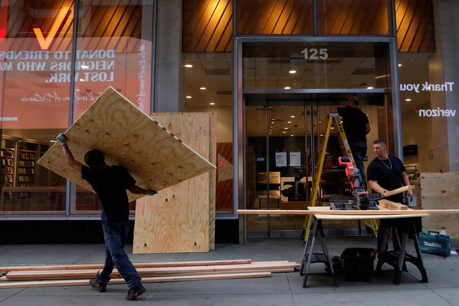 Zwei Männer bauen Holzplatten an ein Schaufenster.