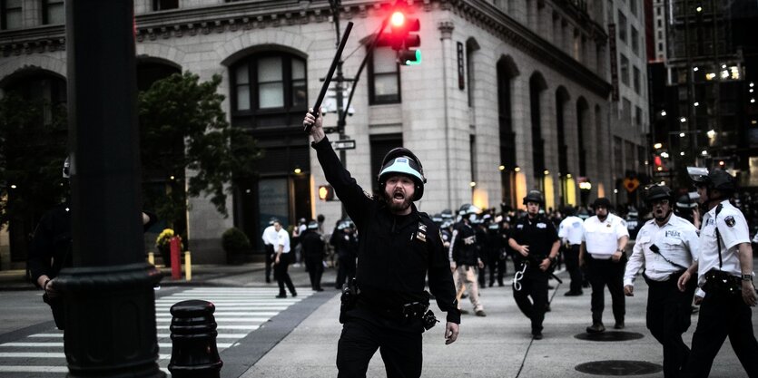 Ein Polizist schreit mit erhobenem Knüppel.