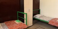 Zwei Betten mit grünem Gestell und Decken
