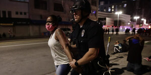 Polizist führt eine Demonstratntin mit Schutzmaske ab