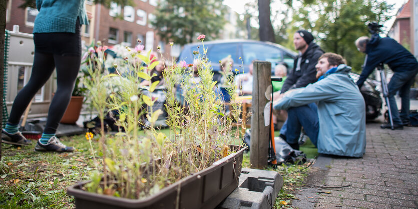 Beim Parking Day nehmen Menschen mit Pflanzen und Stühlen Parkräume ein