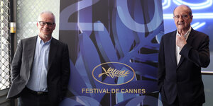 der Festivalleiter und der Festivalpräsident stehen vor einem Banner der Filmfestspiele Cannes
