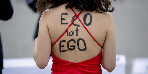 Eco not Ego steht auf einem freien Rücken, rotes Kleid mit großem Ausschnitt