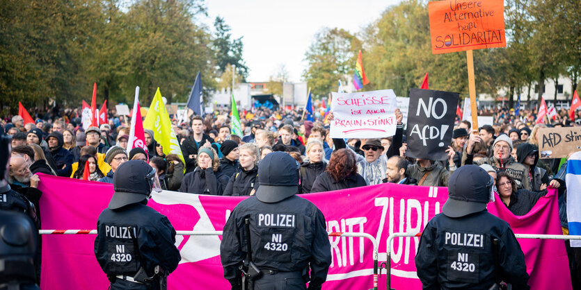 Eine große Anzahl von Demonstranten hinter einer Kette von Polizeibeamten.