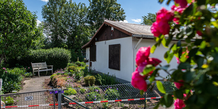 Eine Gartenlaube mit Blumen davor ist mit Plastikband abgesperrt