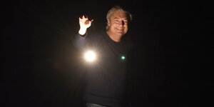 ein Mann hält im Dunkeln eine Lampe in der Hand