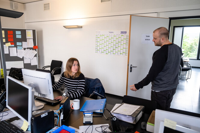 ein Mann und eine Frau in einem Büro gucken sich an