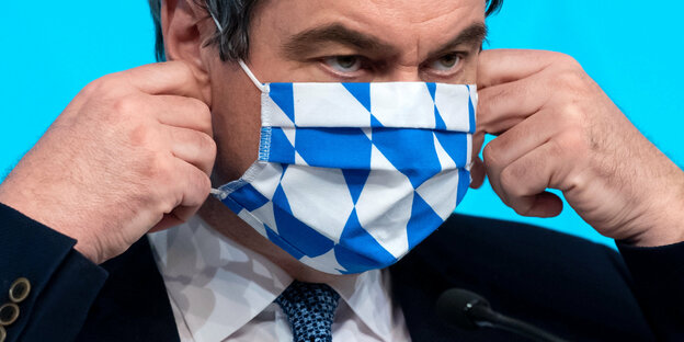 Ministerpräsident Söder richtet seine Gesichtsmaske.