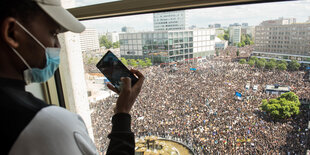 Eine große Demonstration von oben aus einem Fenster fotografiert, im Vordergrund ein anderer Fotograf.